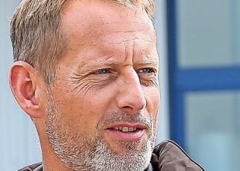Otmar Birkner AutoGyro A middle-aged man with short, light brown hair and a beard looks to the side. He is outdoors, wearing a brown jacket, with a blurred background showing part of a building and a blue window frame.